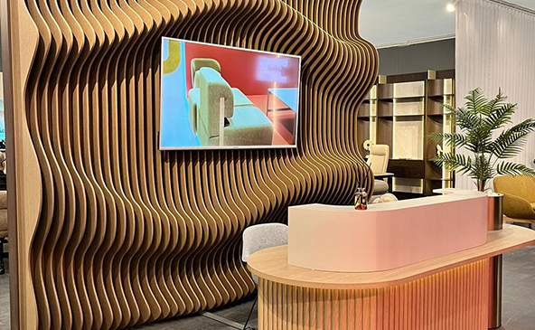 3D parametric wave pattern acoustic PET felt wall panel installed in a modern reception lobby with wooden desk and TV screen – FeltVibe decorative acoustic wall