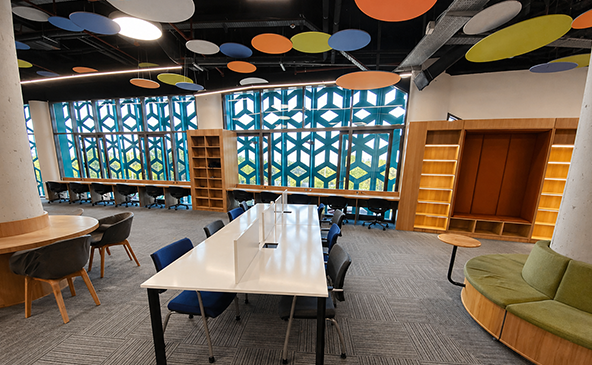 Wide-angle view of colorful Geo Canopy acoustic PET felt ceiling panels at BIM Headquarters Denizli creating a vibrant multicolored suspended ceiling above a modern office workspace