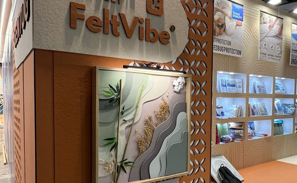 FeltVibe branded exhibition booth entrance at Heimtextile 2026 Frankfurt featuring decorative laser-cut acoustic panels, wave pattern art wall and product display shelves