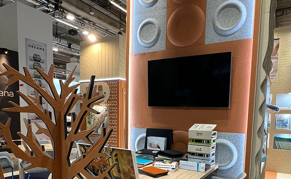FeltVibe exhibition booth at Heimtextile 2026 Frankfurt featuring 3D Cap round grey acoustic PET felt panels on a terracotta orange wall display with TV screen and wooden tree sculpture
