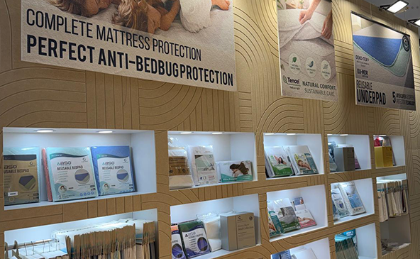 FeltVibe exhibition stand at Heimtextile 2026 Frankfurt displaying complete mattress protection and anti-bedbug protection product range on illuminated shelves with acoustic panel wall