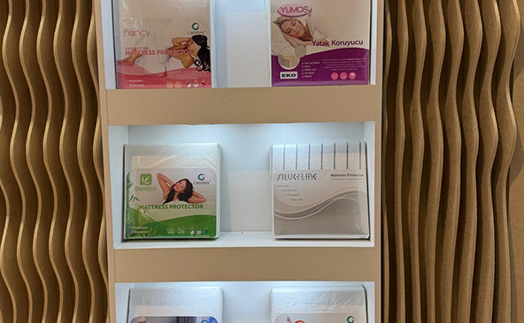 FeltVibe exhibition booth at Heimtextile 2026 Frankfurt showing product display shelves with mattress protectors and acoustic wave wall panels in the background